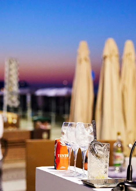 Le coin d’un comptoir portable avec les verres, face à la mer au coucher du soleil