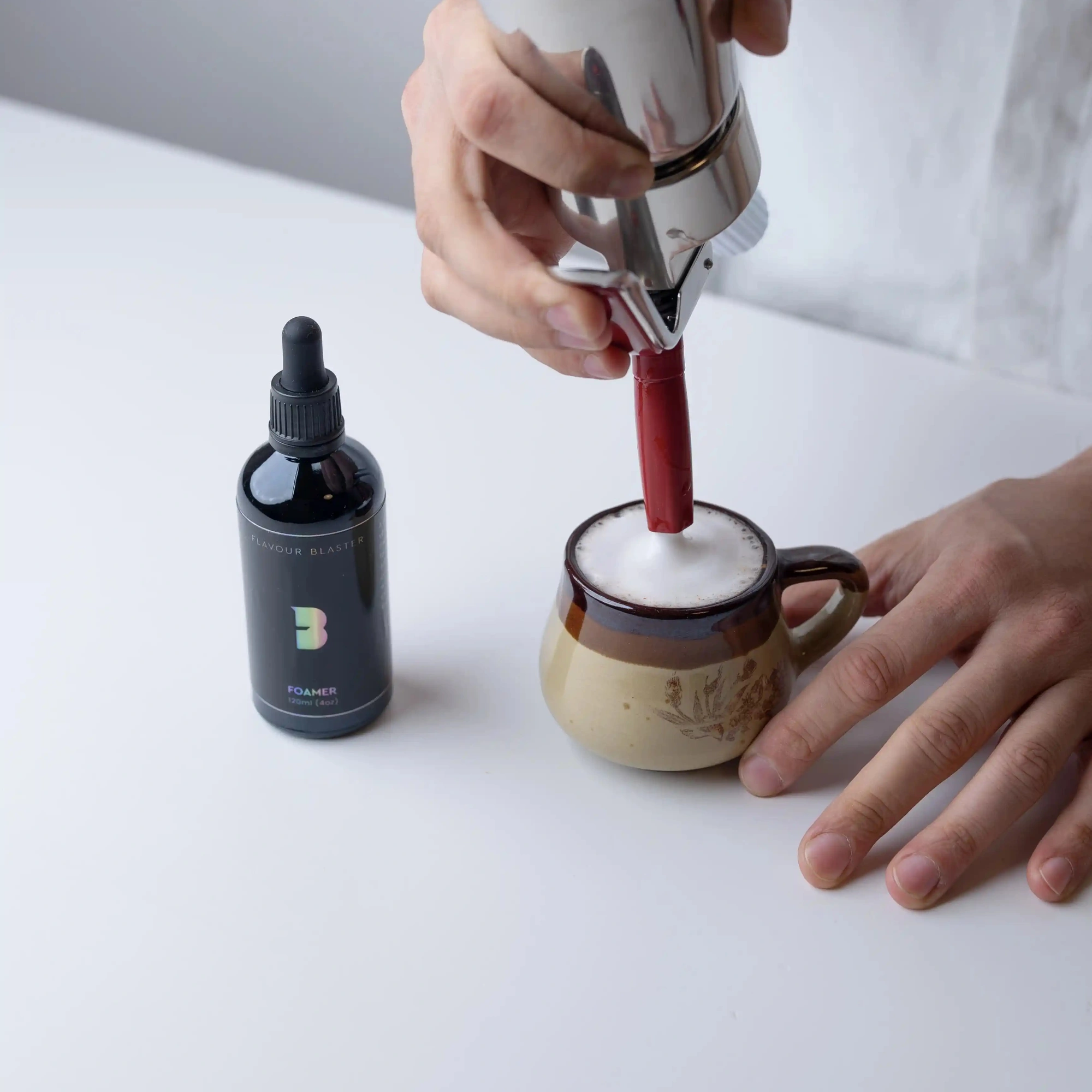 foamer cocktail Flavour Blaster : mousse faite au siphon sur une tasse en céramique, flacon à côté